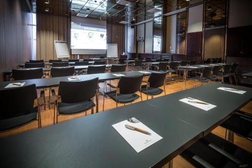 a lecture hall with tables and chairs and a screen at Lapland Hotels Oulu in Oulu