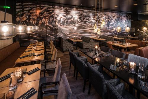 a restaurant with wooden tables and chairs and a mural at Lapland Hotels Oulu in Oulu