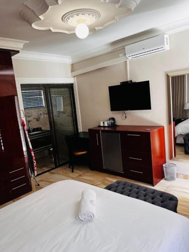 a room with a bed and a flat screen tv at Papiano Boutique Hotel in Bloemfontein