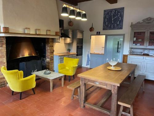 une cuisine avec une table en bois et des chaises jaunes dans l'établissement Gîte de Neufontaine, Maison à la campagne, à Thoiré-sous-Contensor