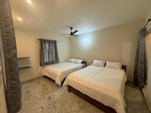 a bedroom with two beds and a ceiling fan at Shivoham Stay Tiruvannamalai in Tiruvannāmalai
