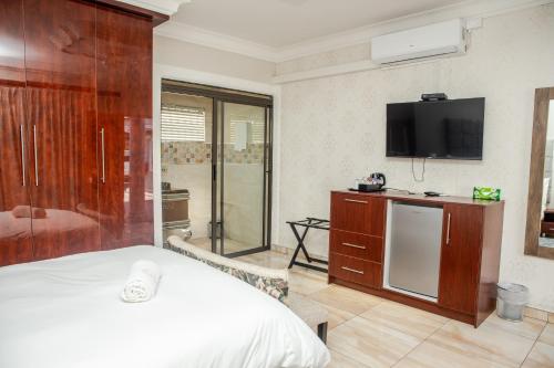 a hotel room with a bed and a television at Papiano Boutique Hotel in Bloemfontein