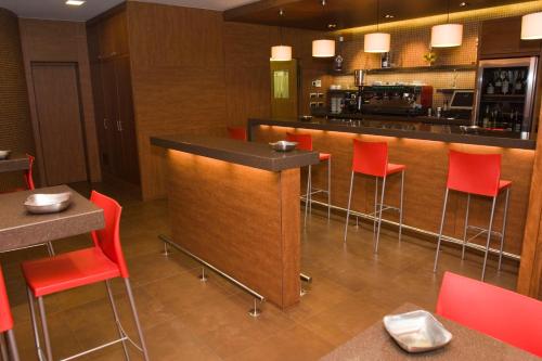 a bar in a restaurant with red chairs at Hotel As Aceas in Narón