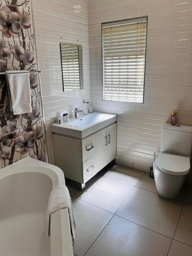 a bathroom with a tub and a sink and a toilet at Papiano Boutique Hotel in Bloemfontein
