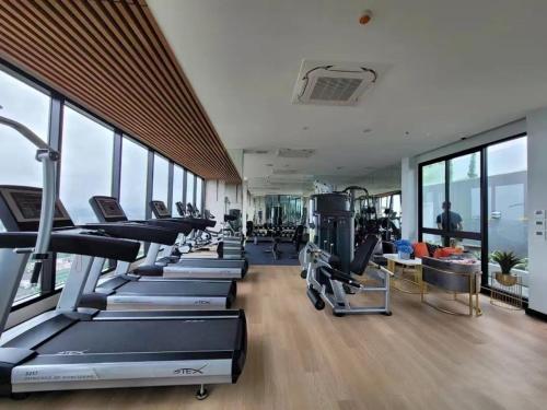 une salle de sport avec une rangée de tapis de course et de machines dans l'établissement The Astra Sky River 2 bedrooms, à Chiang Mai