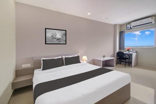 a bedroom with a white and black bed and a desk at Super Collection O ISBT in Guwahati