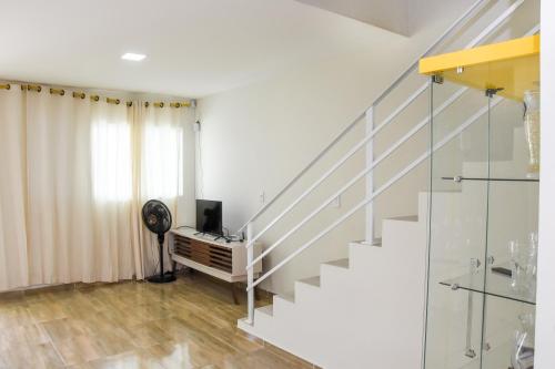ein Wohnzimmer mit einer Treppe und einem TV in der Unterkunft Casa Da Onda in Tamandaré