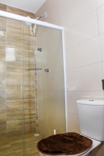 a bathroom with a toilet with a glass shower at Casa Da Onda in Tamandaré
