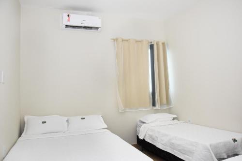 ein Zimmer mit zwei Betten und einem Fenster in der Unterkunft Casa Da Onda in Tamandaré