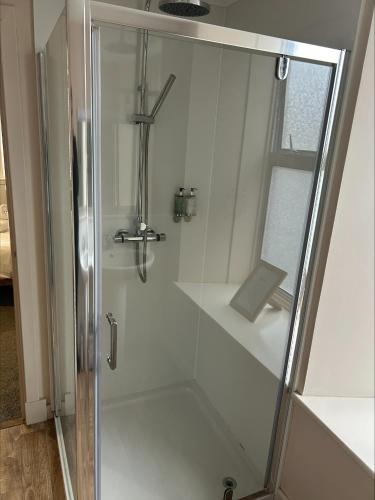 a shower with a glass door in a bathroom at Whisky Capital Inn in Dufftown