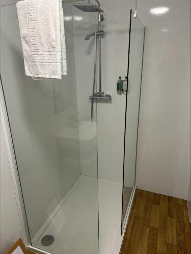 a shower with a glass door and a towel at Whisky Capital Inn in Dufftown
