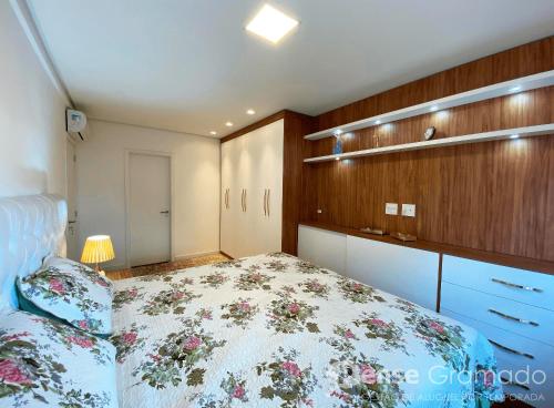 a bedroom with a bed with a floral bedspread at Belluno Boulevard Canela in Canela