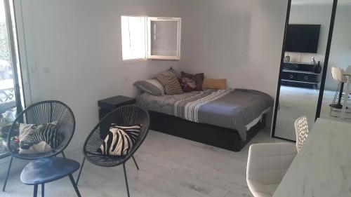 une chambre avec un lit et deux chaises et un miroir dans l'établissement Charmant studio à Sainte-Maxime, 30 m², à Sainte-Maxime