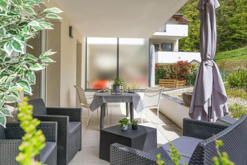 un patio avec une table, des chaises et un parasol dans l'établissement Entre 3 lacswifiterrassecalme, à Cruseilles