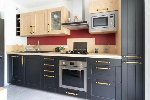 une cuisine avec des armoires noires et un four micro-ondes dans l'établissement Entre 3 lacswifiterrassecalme, à Cruseilles