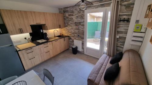 salon z kanapą i kuchnią w obiekcie Appartement T2, terrasse, piscine, clim, proche plage w mieście Marseillan