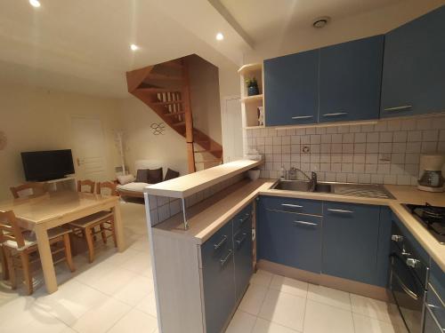 a kitchen with blue cabinets and a living room at Villa de l'epi Grandcamp Maisy in Grandcamp-Maisy