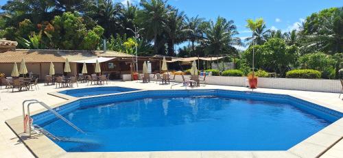 a swimming pool with chairs and umbrellas in a resort at Fantástica Casa 03 Quartos nas belíssimas Praias do Flamengo in Salvador