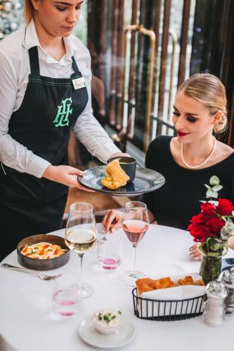 two women serving food at a table with glasses of wine at Esplanade Zagreb Hotel in Zagreb