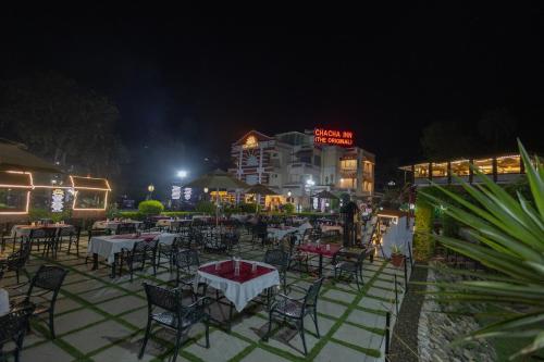 a restaurant with tables and chairs at night at Chacha Inn The Garden Retreat in Mount Ābu