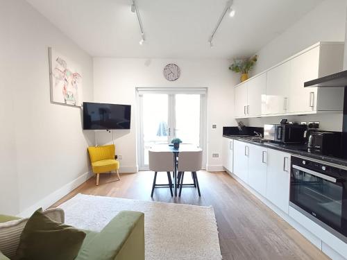 a white kitchen with a table and a yellow chair at Roof terrace 2BED Property CAMDEN free WiFi in London