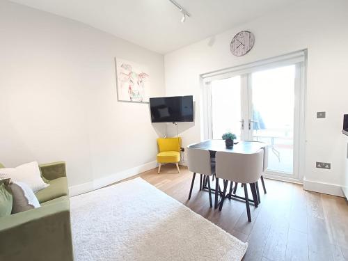 a white living room with a table and a yellow chair at Roof terrace 2BED Property CAMDEN free WiFi in London