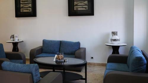 a living room with blue chairs and a table at Hôtel Prestige in Nouadhibou