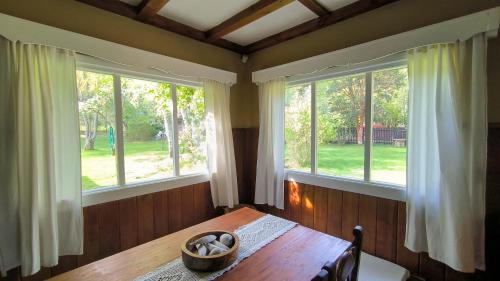 ein Esszimmer mit einem Tisch und zwei Fenstern in der Unterkunft Los Alamos in San Carlos de Bariloche