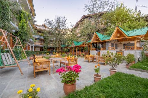 a patio with tables and chairs and flowers at Hide-in Old Manali in Manāli