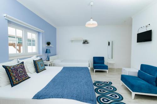 a white bedroom with a large bed and blue chairs at Boutique Hotel - O House Ericeira Hills in Ericeira