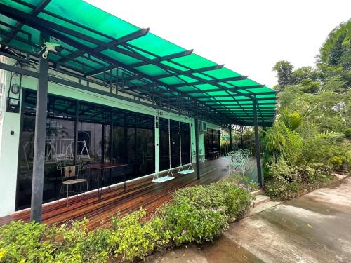 a green pergola on a house with a wooden deck at Chiangmai Courtyard Residence บ้านสวนสวย บ้านถวาย in Bān Sawan