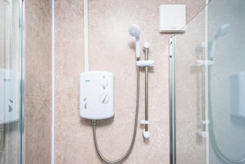 a shower with a blow dryer on a wall at Spacious 4 bed with Parking ideal base for work in Avonmouth
