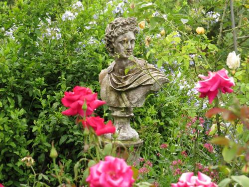 a statue in the middle of a garden with flowers at Gerald's Gift Guest House in Addo