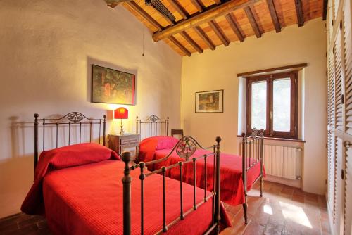 two beds in a bedroom with red sheets at Casale Argentario by PosarelliVillas in Porto Santo Stefano