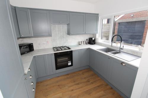 a kitchen with gray cabinets and a sink at Raffaello Cozy Home in Dundonald