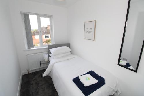 a white bedroom with a bed and a window at Raffaello Cozy Home in Dundonald