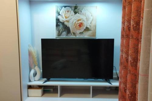 a flat screen tv sitting on a shelf with flowers at simple condo free WiFi free pool in Agus