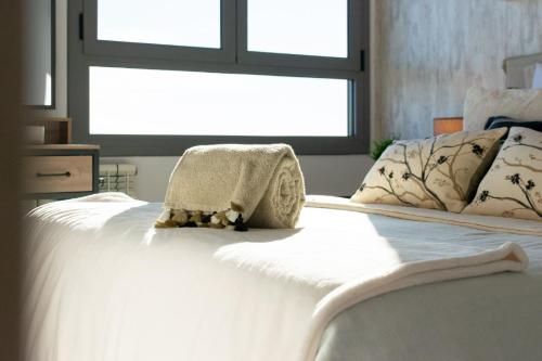 a white bed with a towel on top of it at Penthouse with Private Terrace & Pool Access in Cornellà de Llobregat