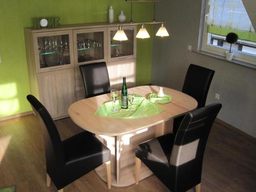 a dining room table with chairs and a bottle of wine at B&U Fewo Scherhag in Alken
