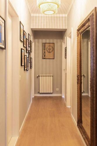 a hallway of a home with a mirror and paintings at Modern apartment 5 mins walking to the Santuary in Fátima