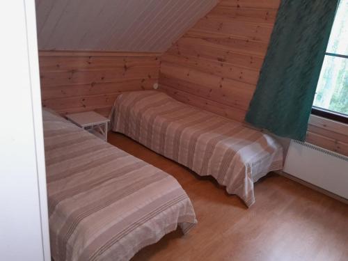 a bedroom with two beds in a room with wooden walls at Katajaranta in Karvonen
