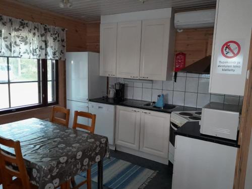 a kitchen with white cabinets and a table and a table and chairs at Katajaranta in Karvonen