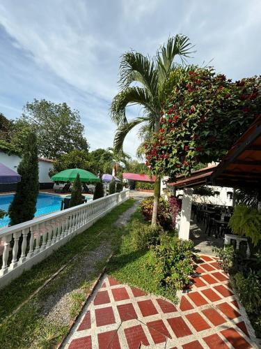 a resort with a swimming pool and a palm tree at Hotel campestre París soleil in Mariquita