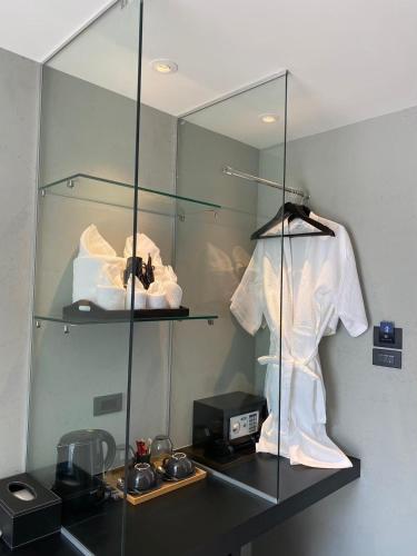 a glass shelf with a white shirt and a mirror at Nirundorn Resort Chaam in Cha Am