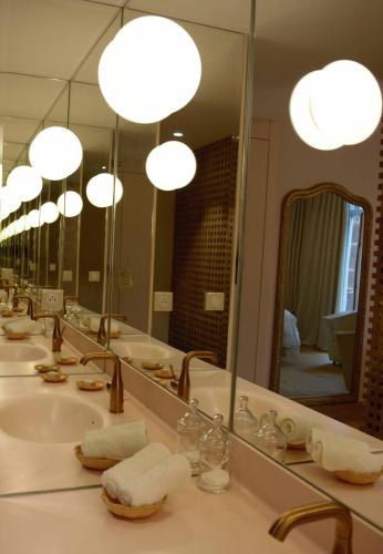 La salle de bains est pourvue de 3 lavabos, de miroirs et de serviettes. dans l'établissement Hôtel Restaurant Auprès d'Angèle, à Marcillac-Vallon