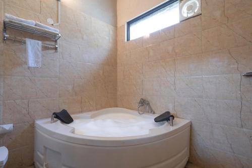 a bathroom with a bath tub and a sink at The Tattwaa Corbett Spa and Resort in Rāmnagar