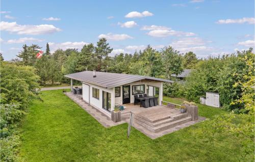 a small white house with a deck in a yard at Four-Bedroom Holiday Home In Juelsminde in Sønderby