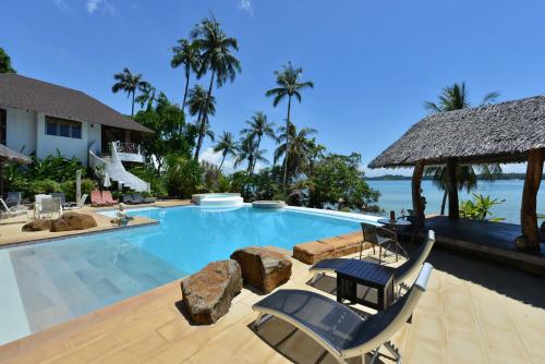a swimming pool at a resort with two lounge chairs at Koh Mak Cococape Resort in Ko Mak