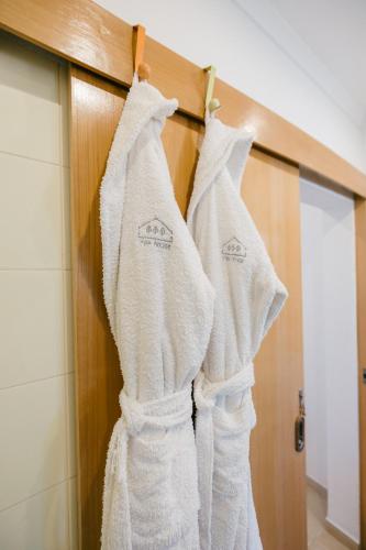 two white towels hanging on a door in a bathroom at Tree House - Casa Figueira in Sesimbra