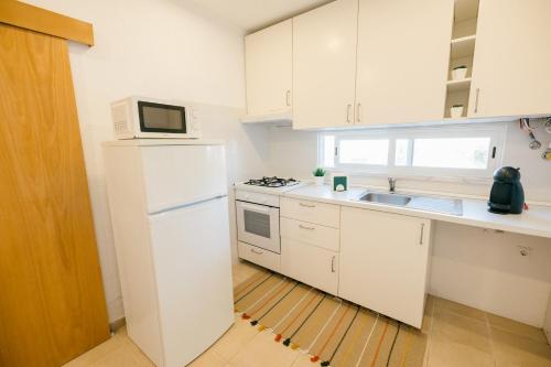 a white kitchen with a sink and a microwave at Tree House - Casa Figueira in Sesimbra